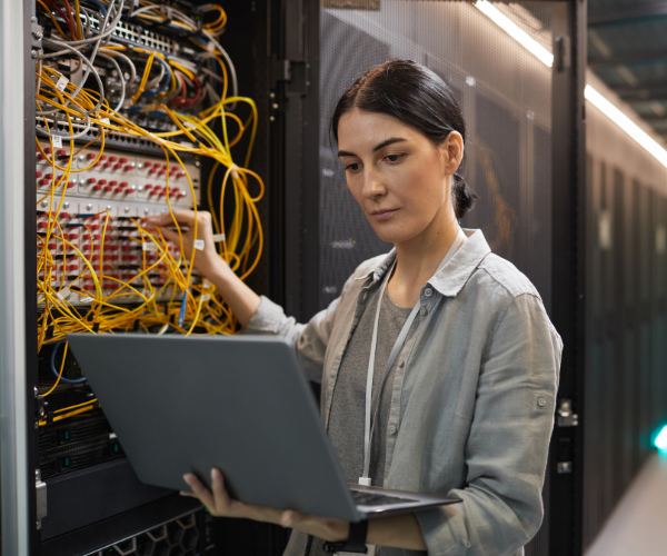 Vrouw bezig met de IT infrastructuur bij een serverkast.