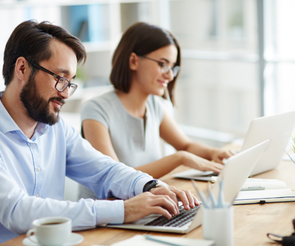 Twee kantoormedewerkers aan het werk op een laptop.